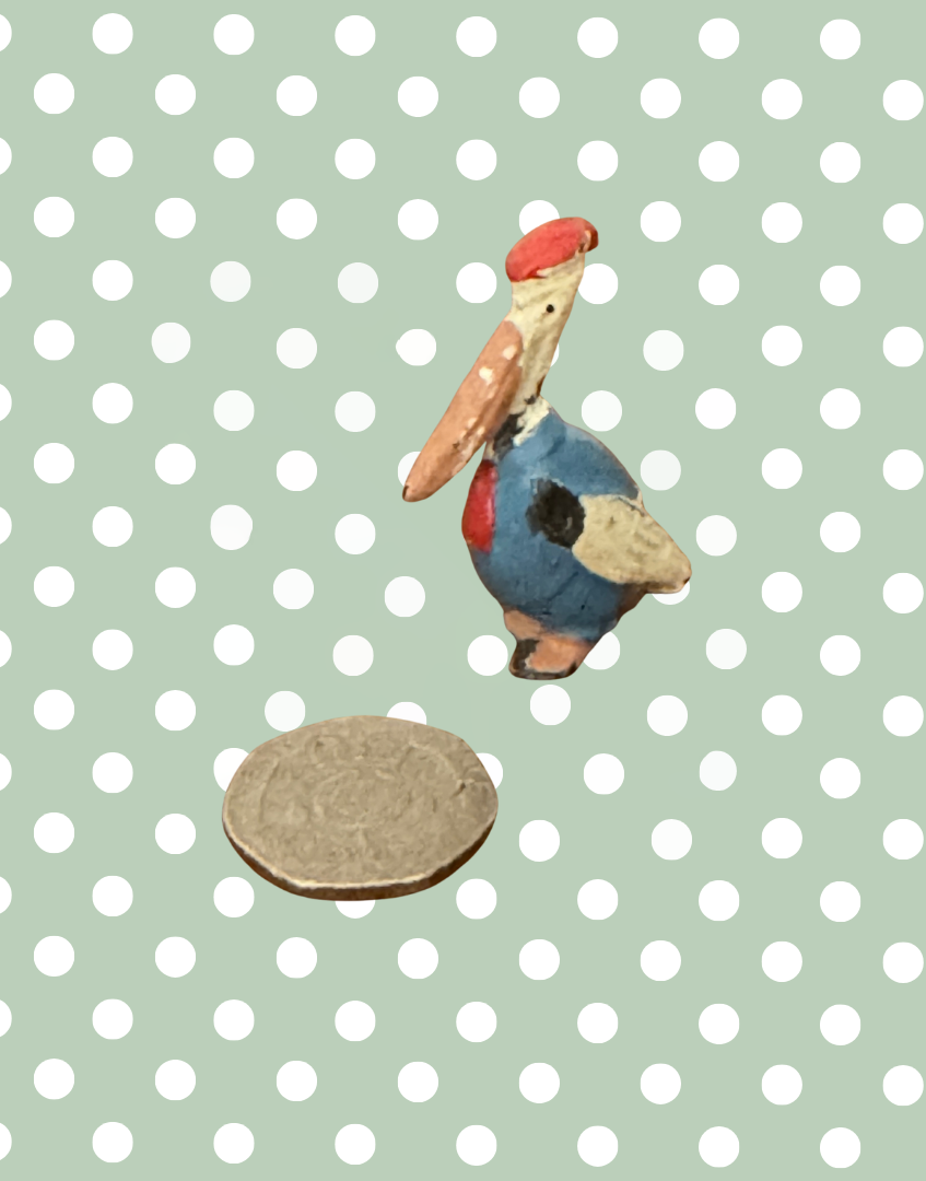 miniature cadbury cococub pelican lead figurine next to twenty pence coin to show scale