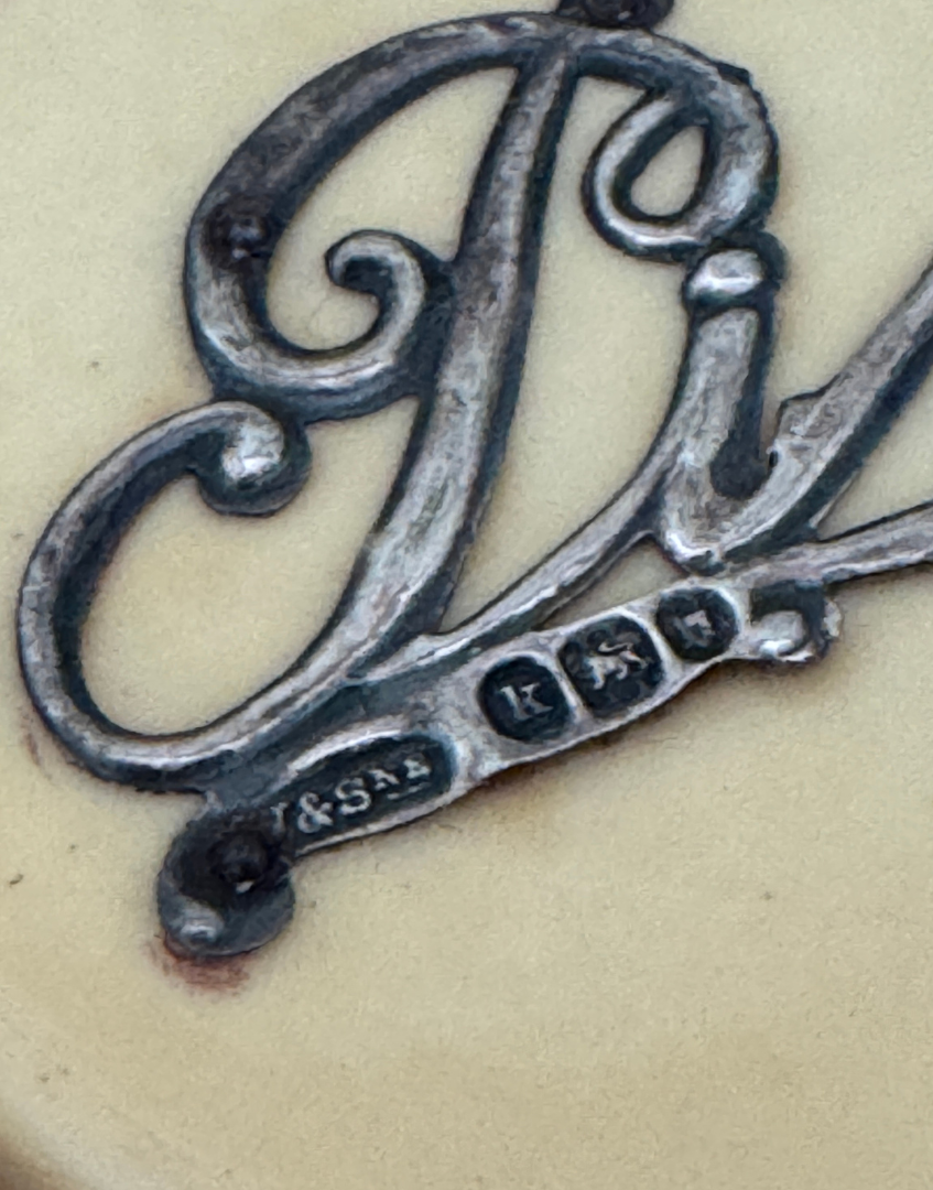 A close up of sterling silver hallmarks on Pin lettering on antique pin pot lid