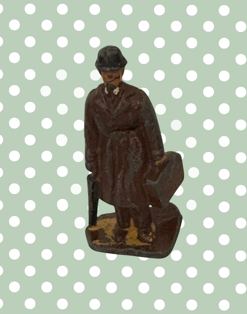 vintage figurine of hand painted gentleman in brown trench coat