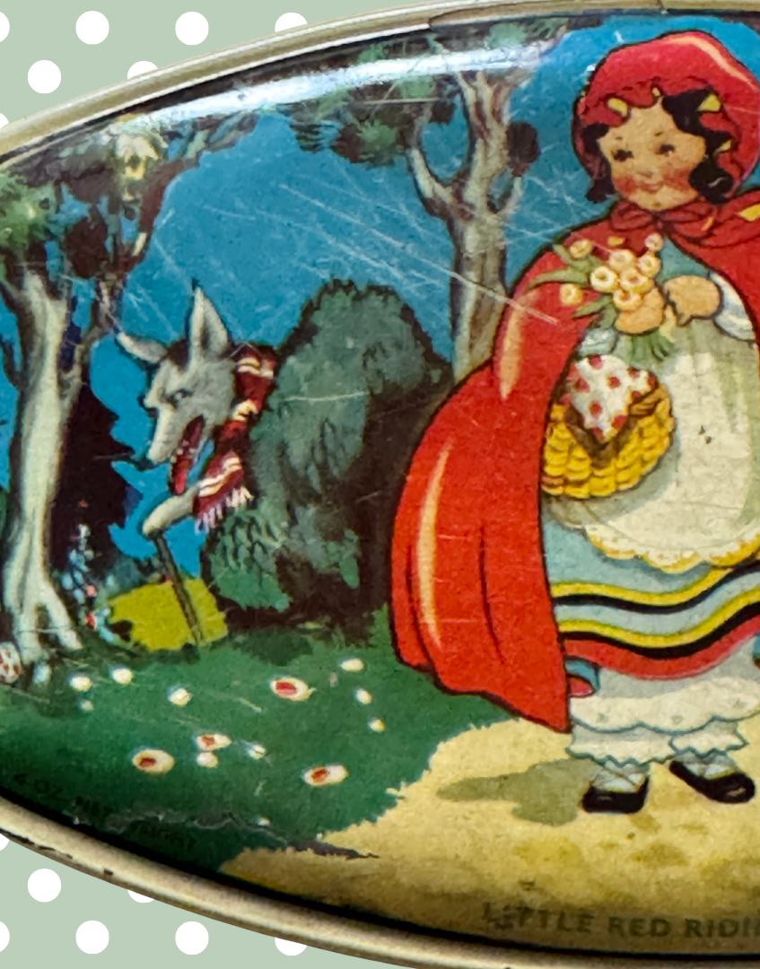 Close up left side of 1930s Little Red Riding Hood advertising tin showing wolf illustration, woodland path and flower detail on lid artwork