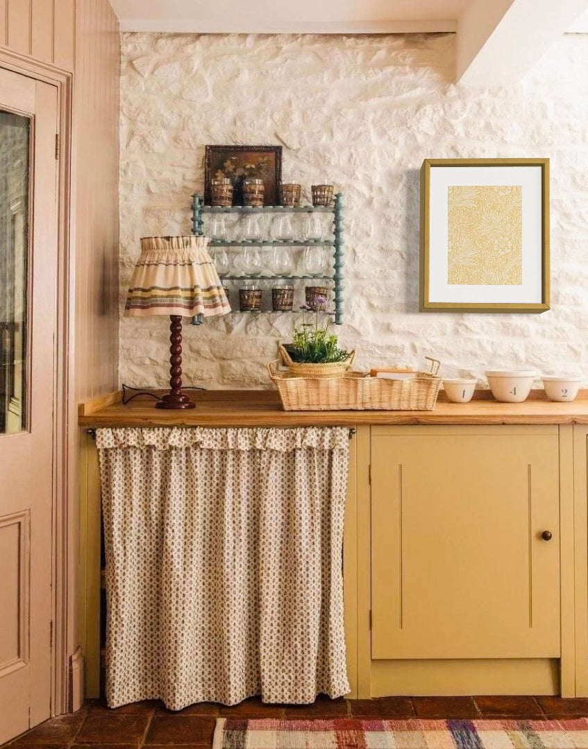 Cottagecore styled kitchen interior with yellow painted units and William Morris framed wall decor
