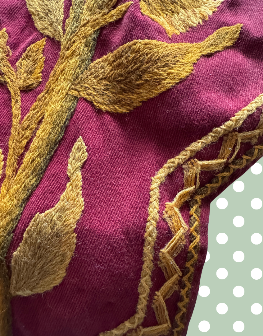 Close up of detailed crewel wool stitching and decorative linear embroidery outlining the stepped edge of the antique Arts and Crafts pelmet.