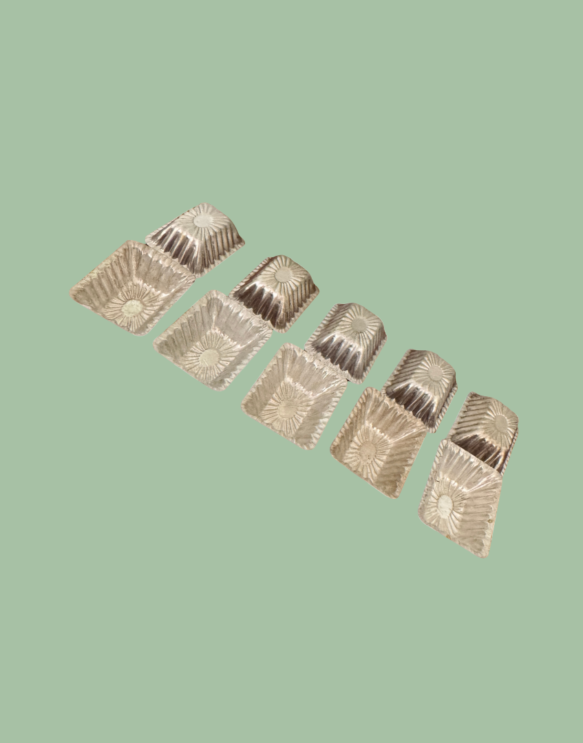 Ten vintage aluminium chocolate moulds displayed together showing rectangular shape, scalloped edges and aged patina