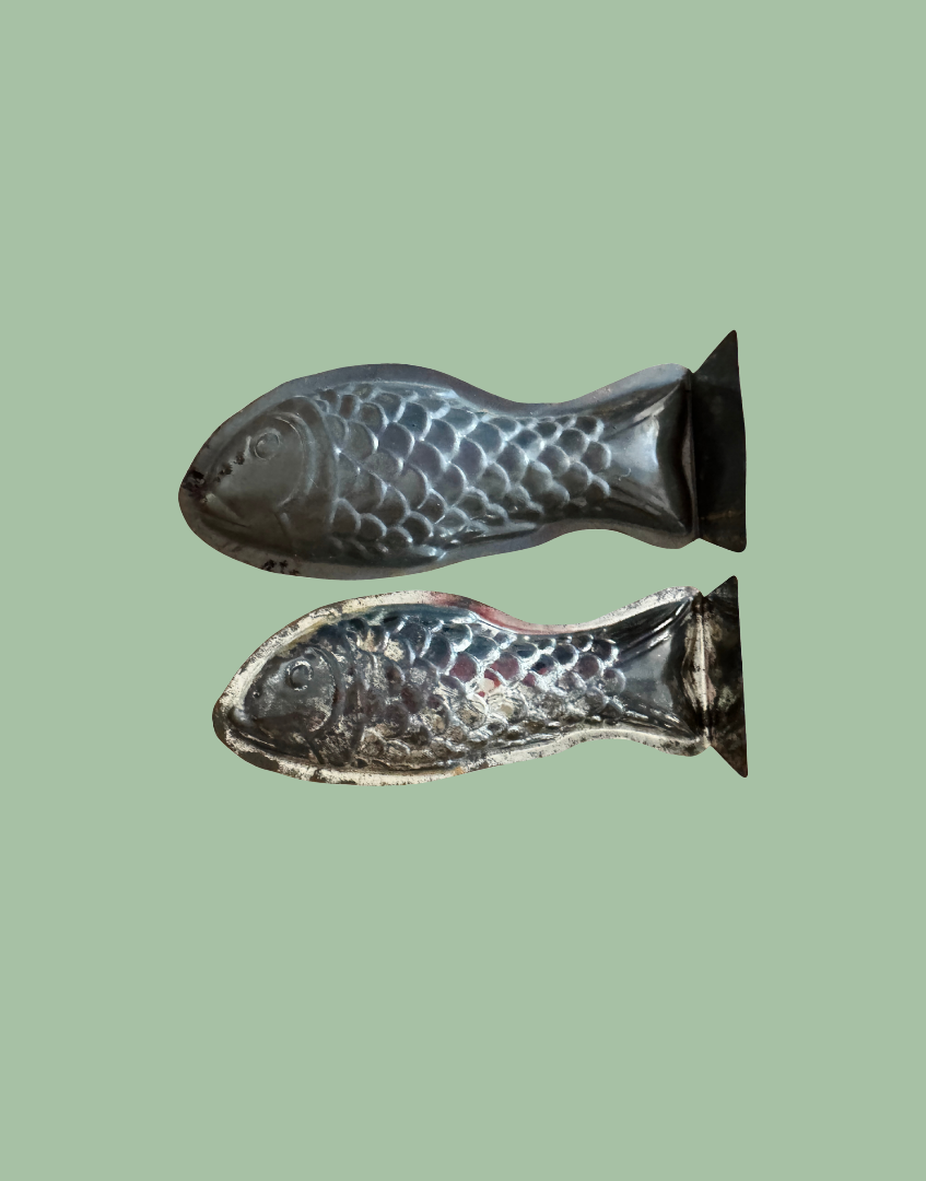 Underside view of two vintage tinplate fish moulds showing construction details and original culinary design
