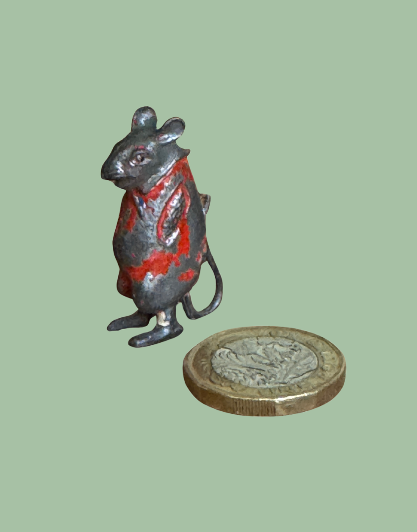 Miniature lead mouse toy next to one pound coin