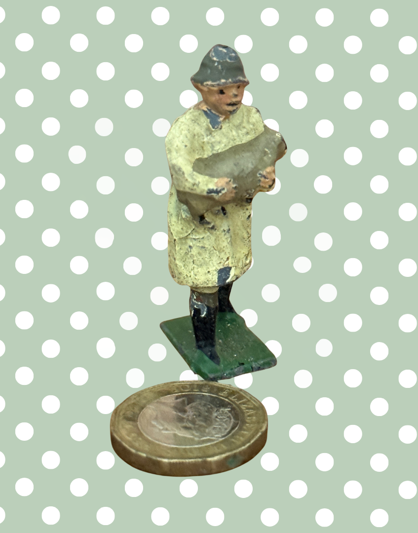 traditionally dressed britains farmer in coat, boots and hat carrying a lamb next to a one pound coin for scale