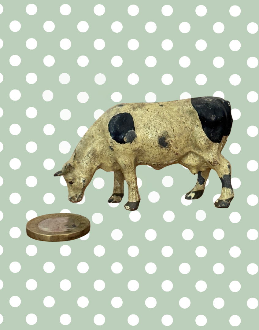 hand painted britains lead cow figurine next to one pound coin for scale