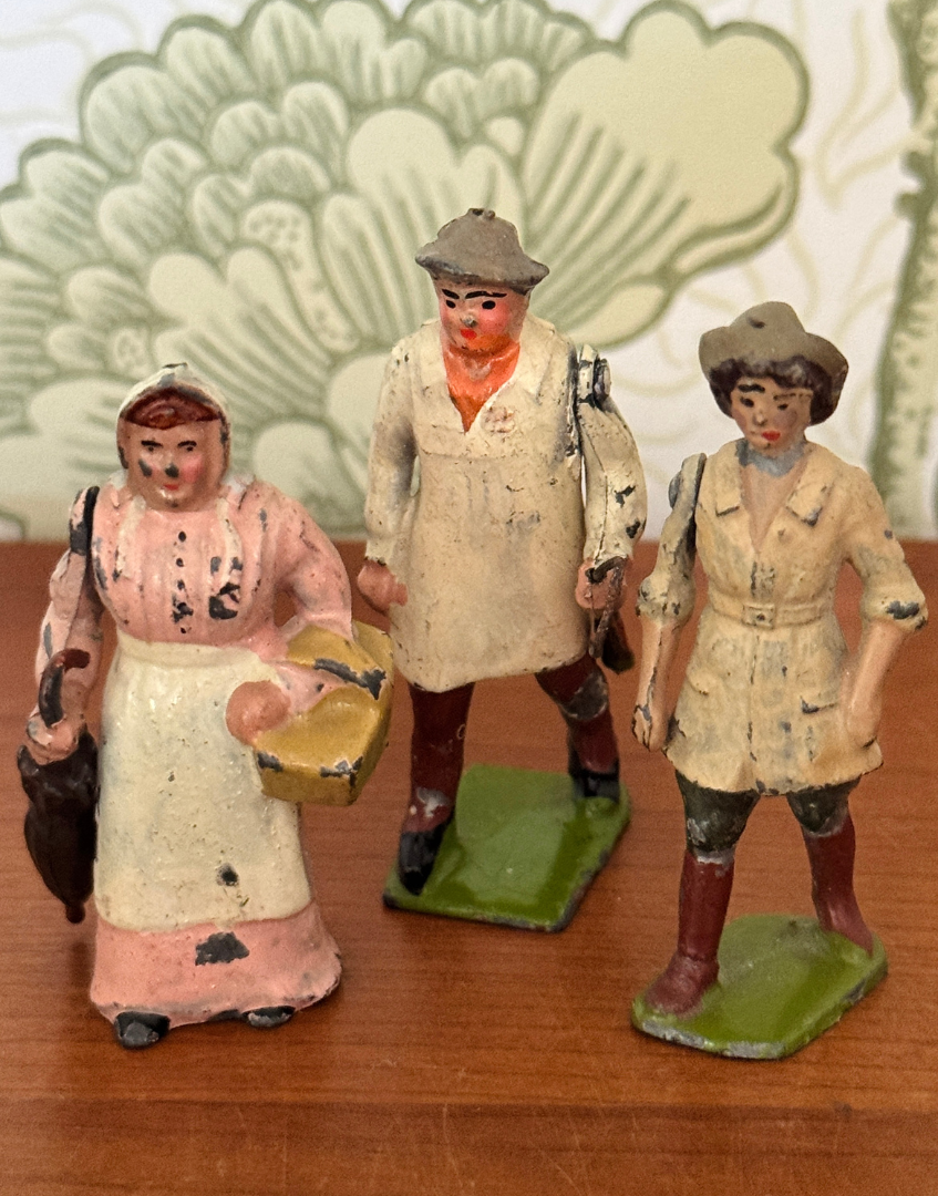 Three vintage Britains Home Farm Series lead figures including Wife with Umbrella, Carter with Whip and Land Girl displayed together