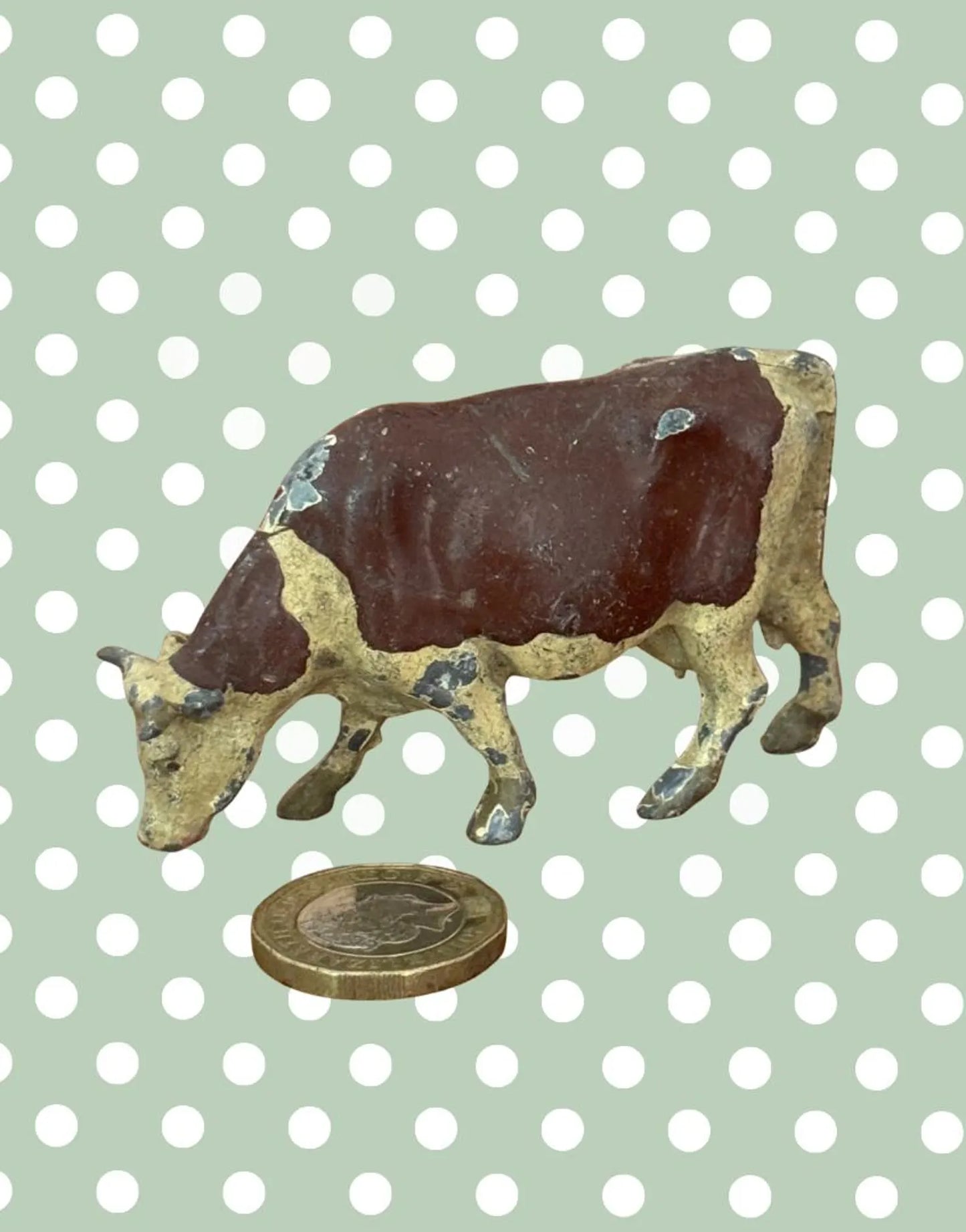 britains farm series vintage lead cow fihurine next to a pound coin for scale