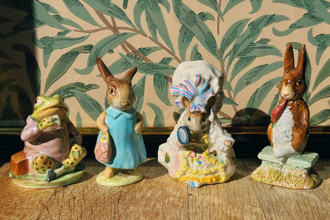 Four vintage Beswick Beatrix Potter figurines — Jeremy Fisher, Mrs Flopsy Bunny, Lady Mouse and Fierce Bad Rabbit - displayed in a row on a wooden shelf.