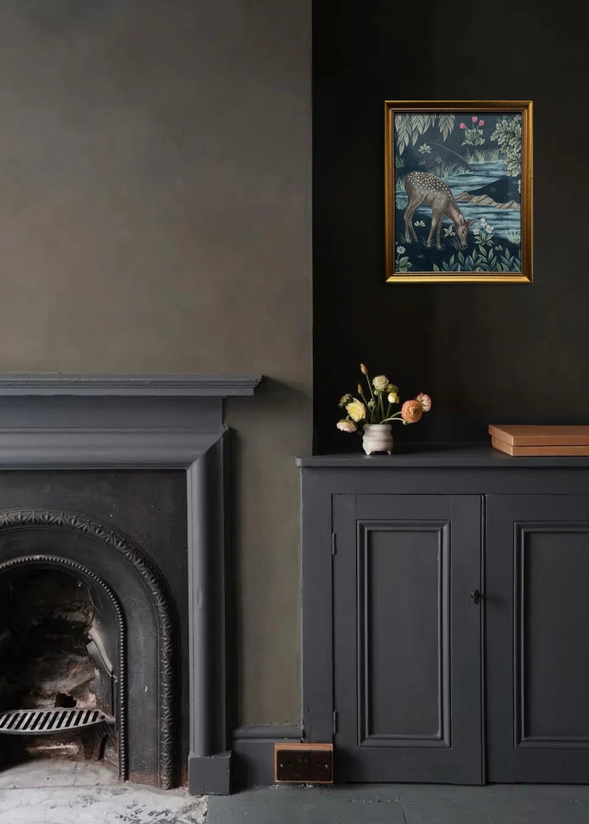 Dark interior with fireplace, cabinet, and vintage gold framed artwork on a dark wall.