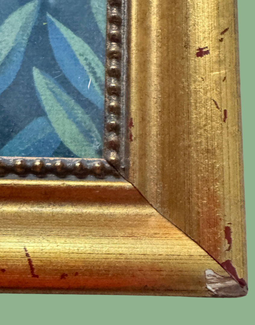 Close-up of the corner of a distressed gold picture frame with peeling paint and a beaded inner border.