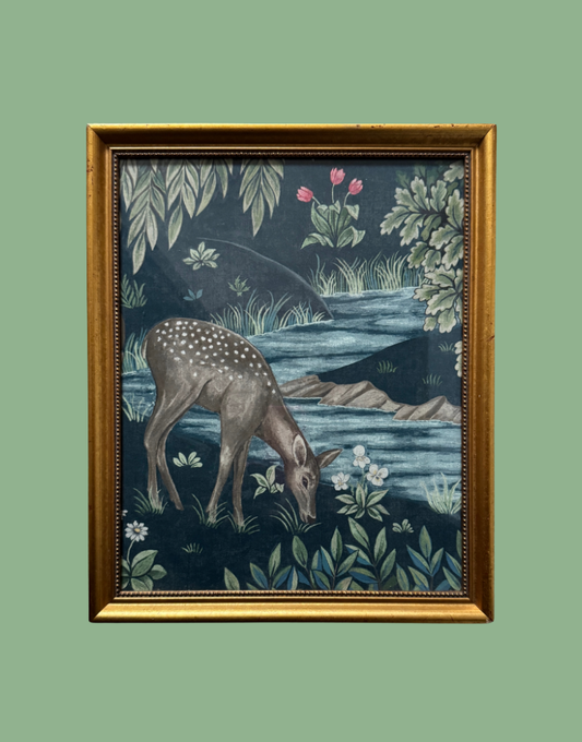 A framed William Morris art print depicting a spotted deer grazing by a river, with a dark blue background and green foliage, enclosed in a gold frame.