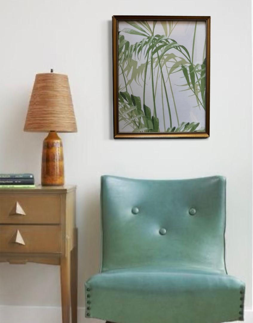 Tropical greem palm leaf print in vintage gold frame in retro interior wih blue leather chair.