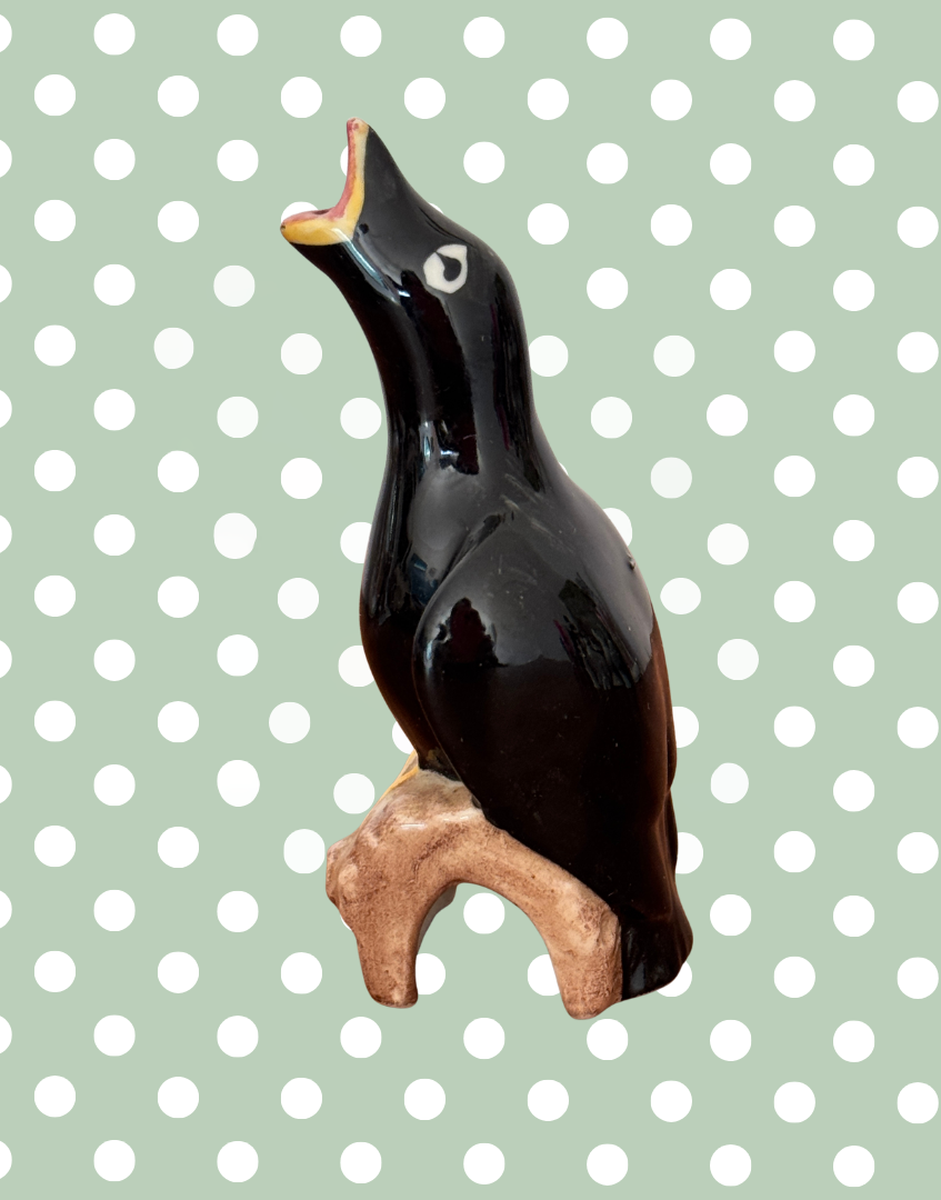 Side view of vintage ceramic blackbird on log baking tool