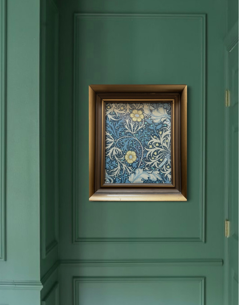 Vintage gold framed William Morris print with floral design on a green paneled wall. 