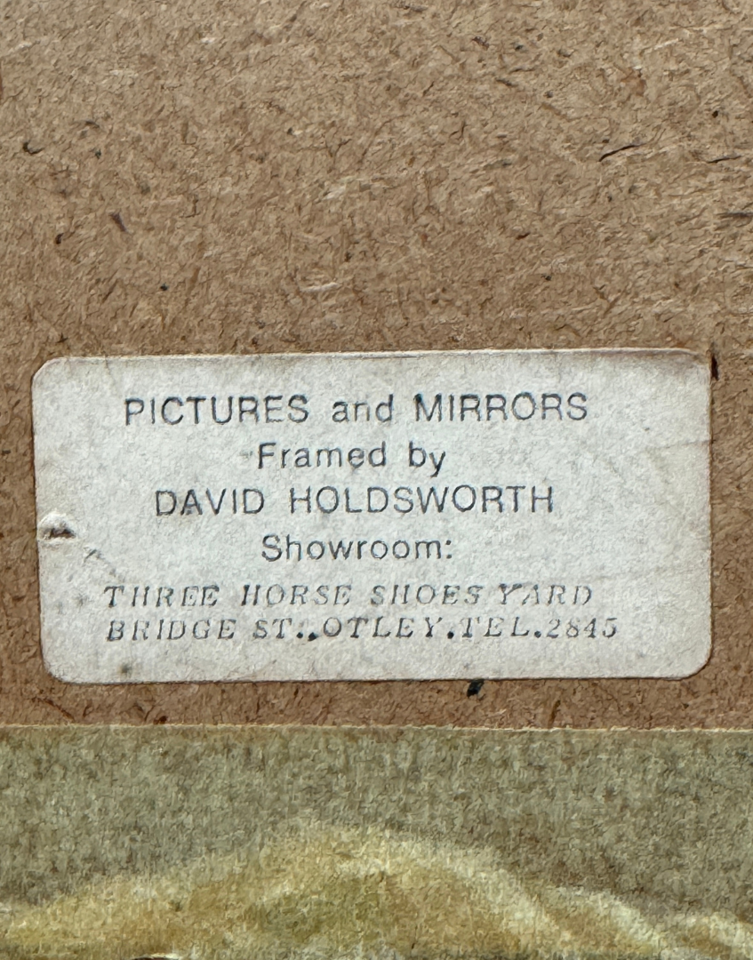 Label on a framed picture with text about framing services and contact details.
