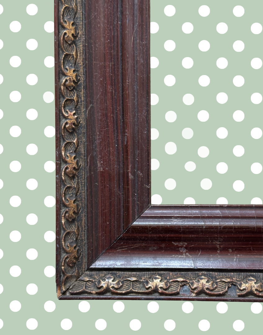 Detailed antique picture frame showing dark wood grain and ornate metal embellishment.
