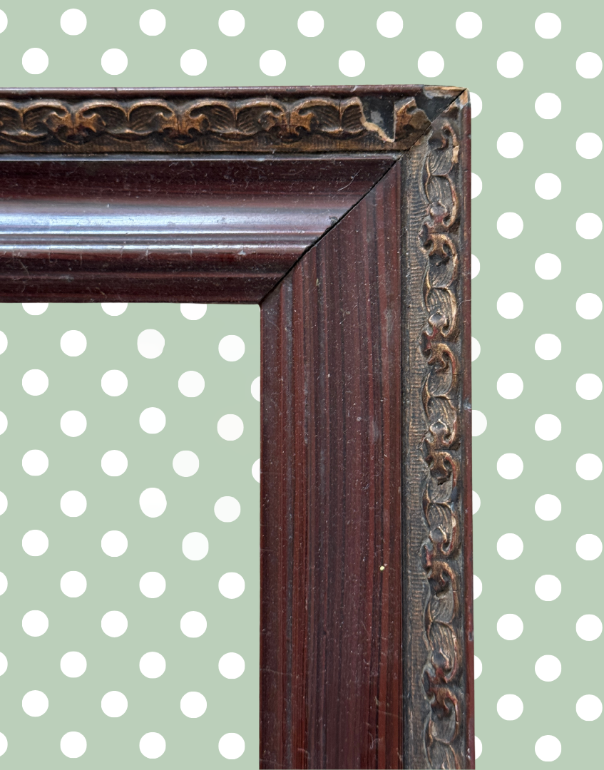 Close up of antique wood frame corner with decorative metal detailing and age wear.