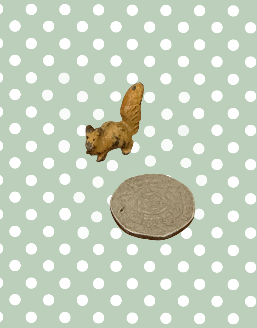 miniature hollow cast lead vintage squirrel toy next to a twenty pence coin for scale reference
