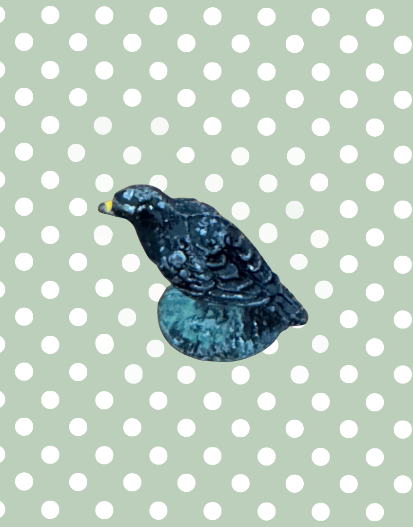 close up of balck crow with yellow beak lead toy with fether detailing and yellow beak