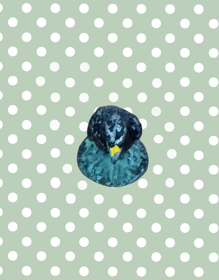 top side view of black metal crow on green stand figurine