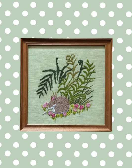 Close up of embroidered sleeping country mouse surrounded by pink floral detail and textured stitching