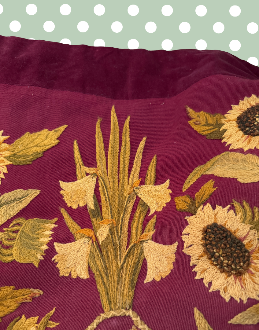 Close up of the antique embroidered panel showing detailed crewel wool stitching, floral forms and the rich plum twill ground.