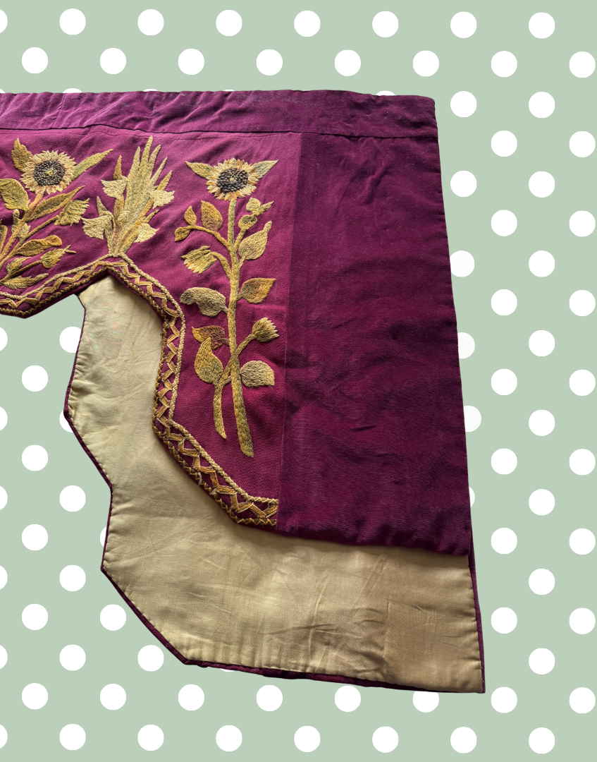 Front right section of the antique pelmet showing the embroidered front and the protective lining visible behind the textile.