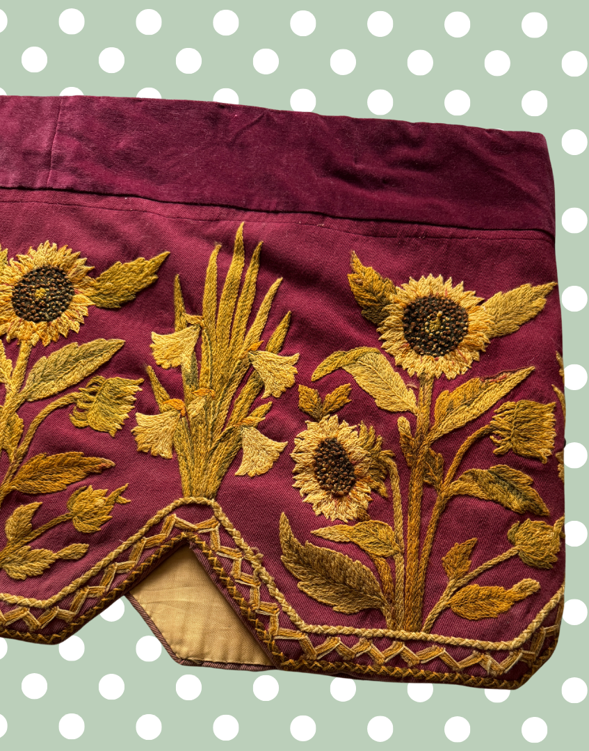 Front mid right section of the antique crewelwork pelmet showing detailed floral embroidery against the deep plum ground.