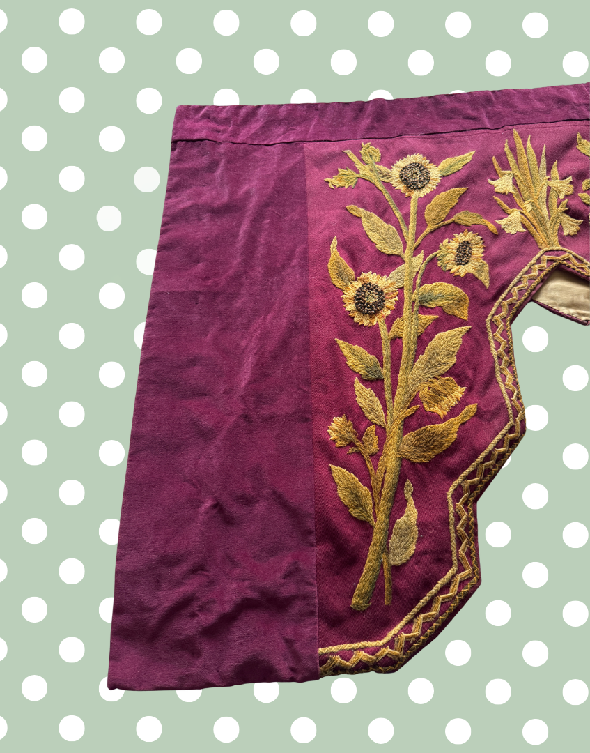 Front left section of the antique embroidered pelmet showing large scale floral crewelwork and the asymmetric stepped design.