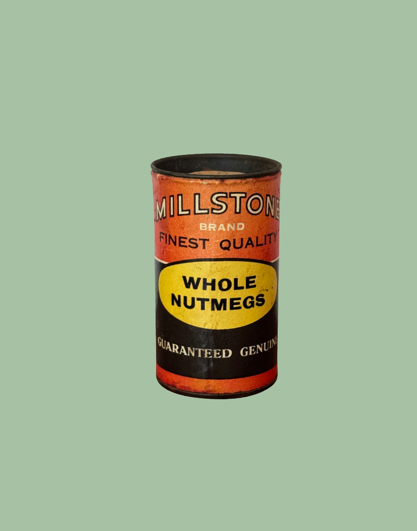 A vintage Millstone Brand Whole Nutmegs canister, featuring a rusted orange and black label with a yellow oval center.
