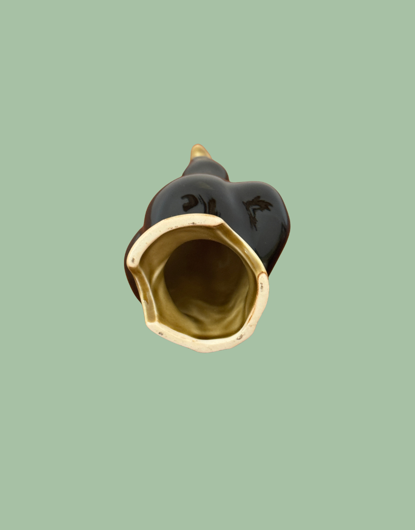 Underside of the vintage ceramic pie bird showing the hollow interior, glazed olive-toned base and unglazed rim.