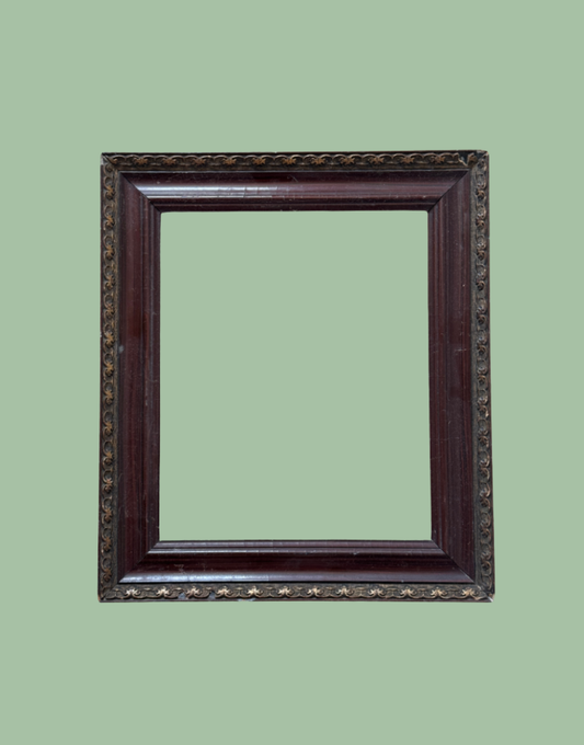 An ornate rectangular picture frame with a dark reddish-brown wood finish and gold star details, shown against a solid sage green background.