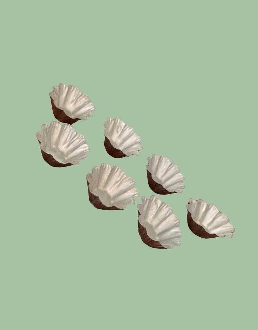 Seven vintage petit four moulds arranged in rows showing matching fluted design and aged metal character