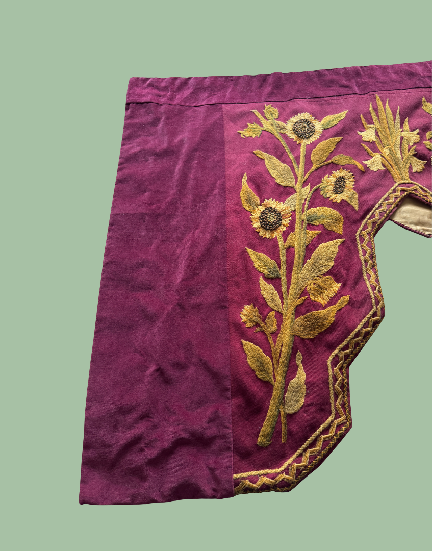 Front left section of the antique embroidered pelmet showing large scale floral crewelwork and the asymmetric stepped design.