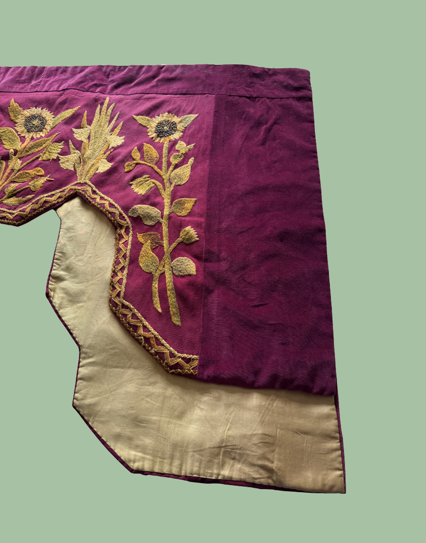 Front right section of the antique pelmet showing the embroidered front and the protective lining visible behind the textile.