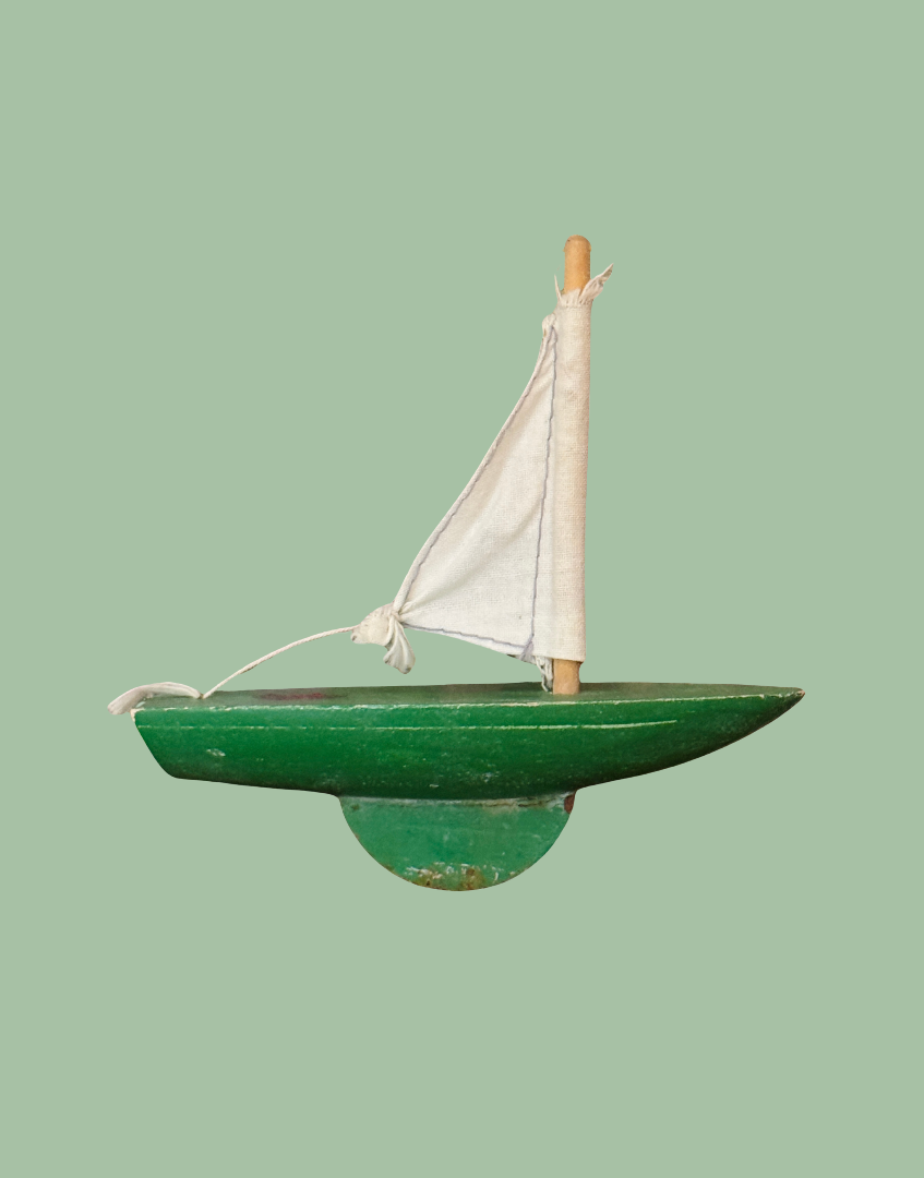 Side view of vintage Star Yachts No. 0 pond yacht showing its apple green wooden hull, sail and weighted keel.