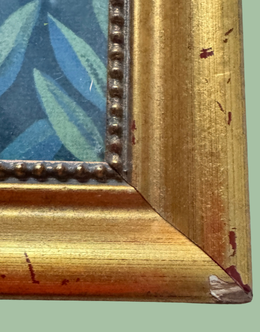 Close-up of the corner of a distressed gold picture frame with peeling paint and a beaded inner border.