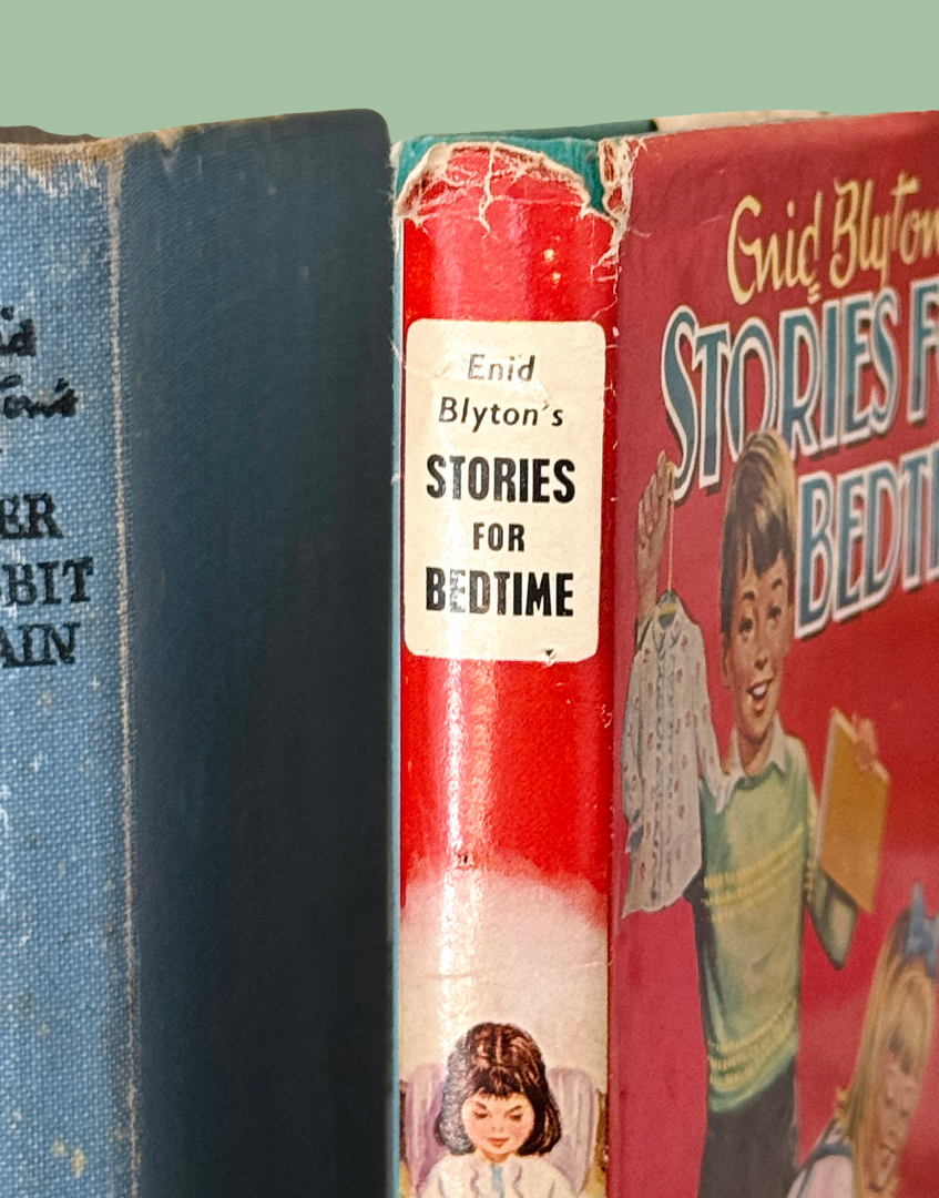 Close-up of vintage hardcover children's books standing upright, with the center book showing the spine title 'Enid Blyton's Stories for Bedtime' on a red cover.