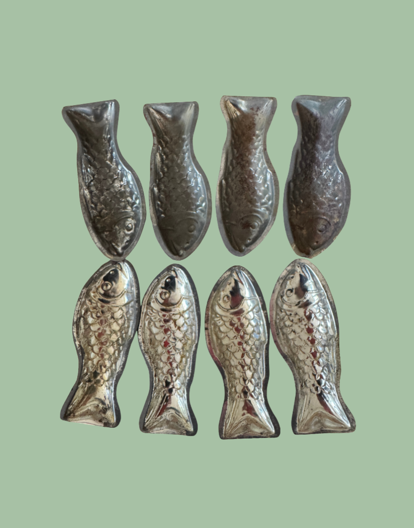 Reverse view of eight vintage fish shaped tinplate moulds showing original flat tail extensions used for holding in production trays