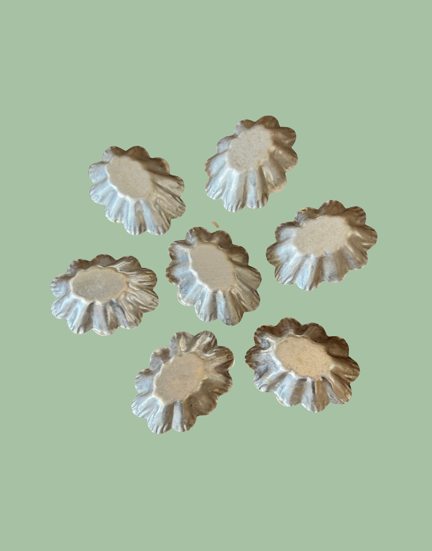Underside view of seven vintage petit four moulds showing original metal construction and vintage patina