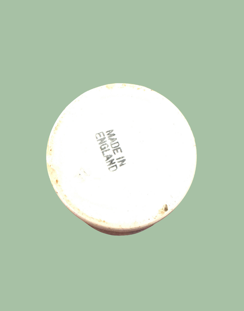 The circular white base of a ceramic vessel, showing the black printed text 'MADE IN ENGLAND', isolated on a solid sage green background.