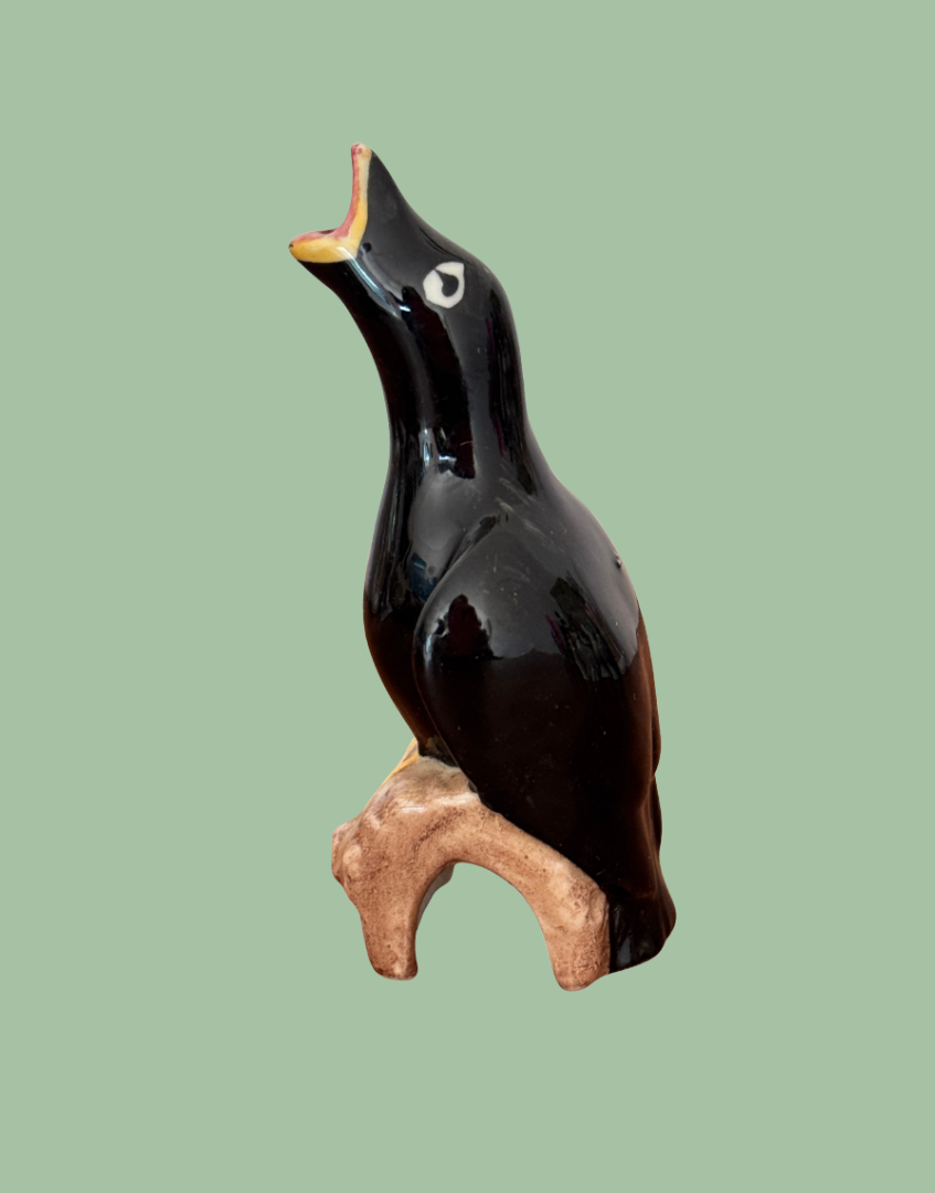 Side view of vintage ceramic blackbird on log baking tool
