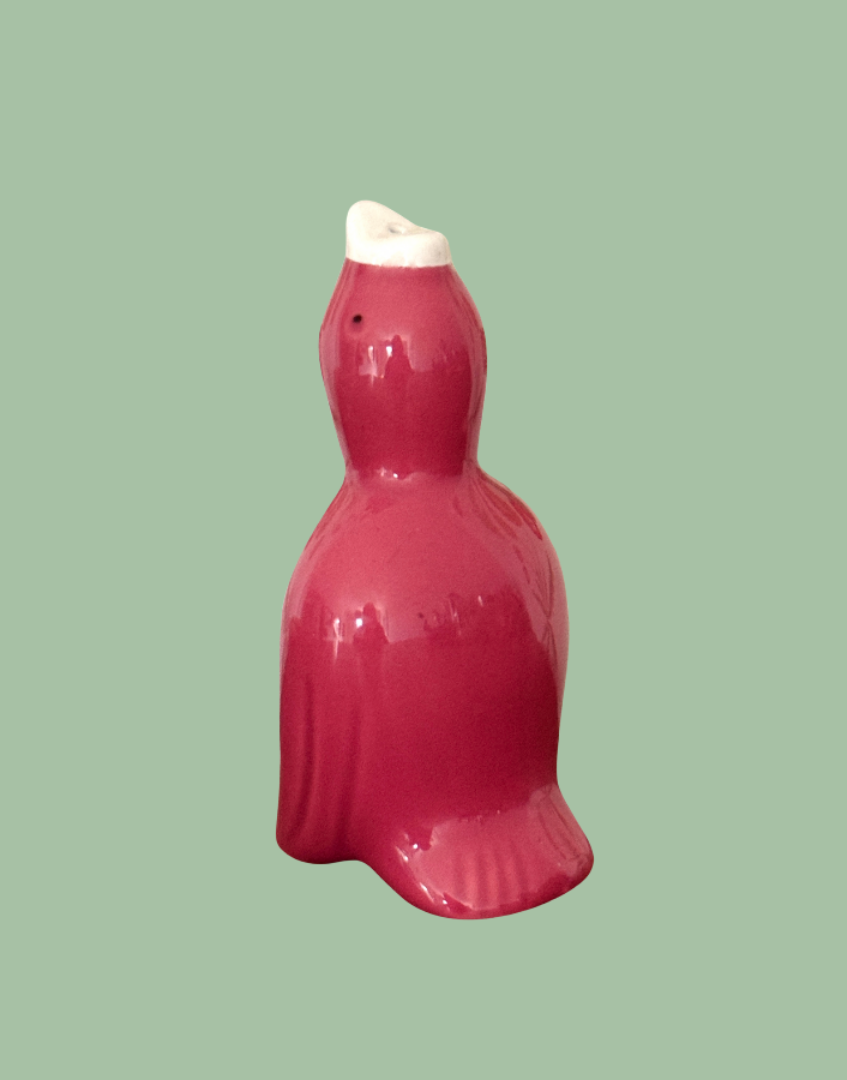 Side view of pretty dark pink ceramic glossy pie bird with feather detail, white beak and black eyes.