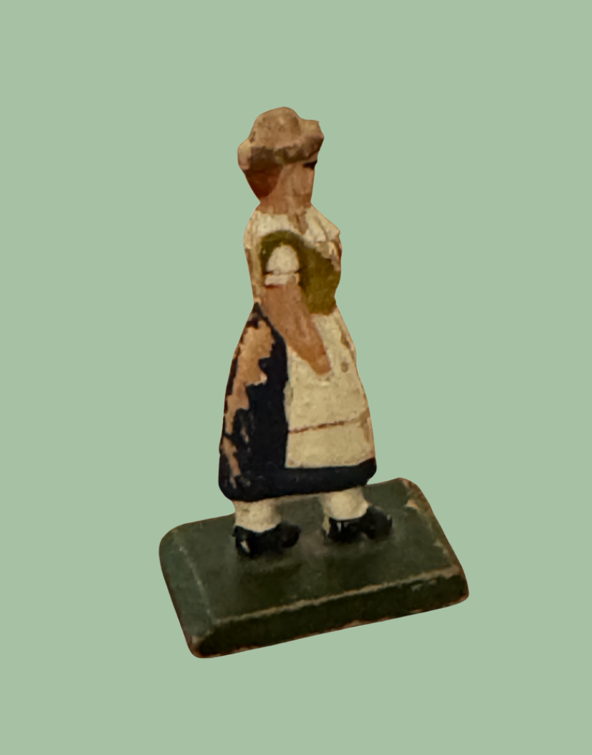 Small figurine of a German milk maid woman in traditional period attire on a polka dot background
