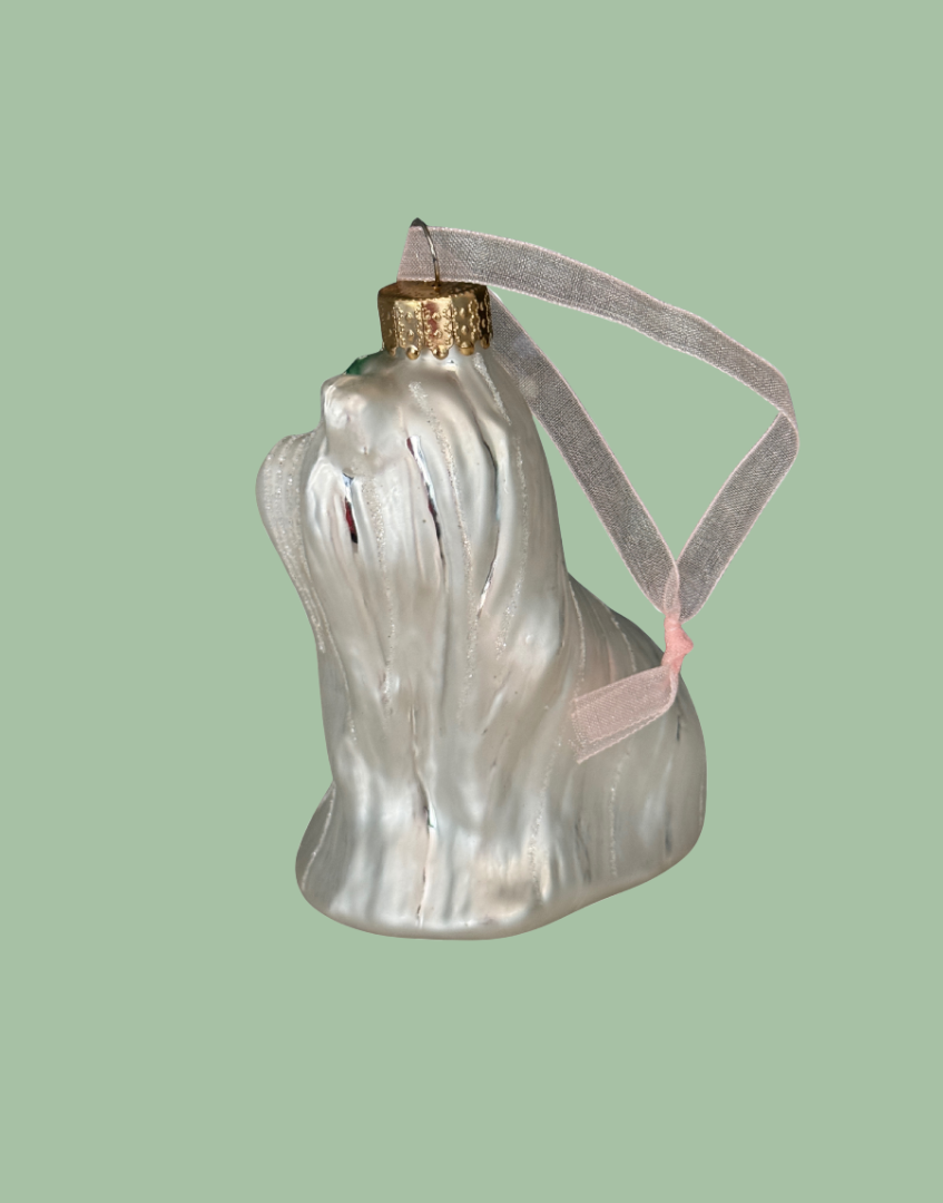 Glass ornament shaped like a dog with a pink ribbon on a polka dot background