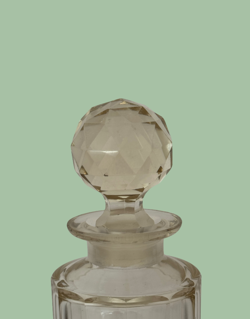 Clear glass bottle with a textured stopper on a polka dot background