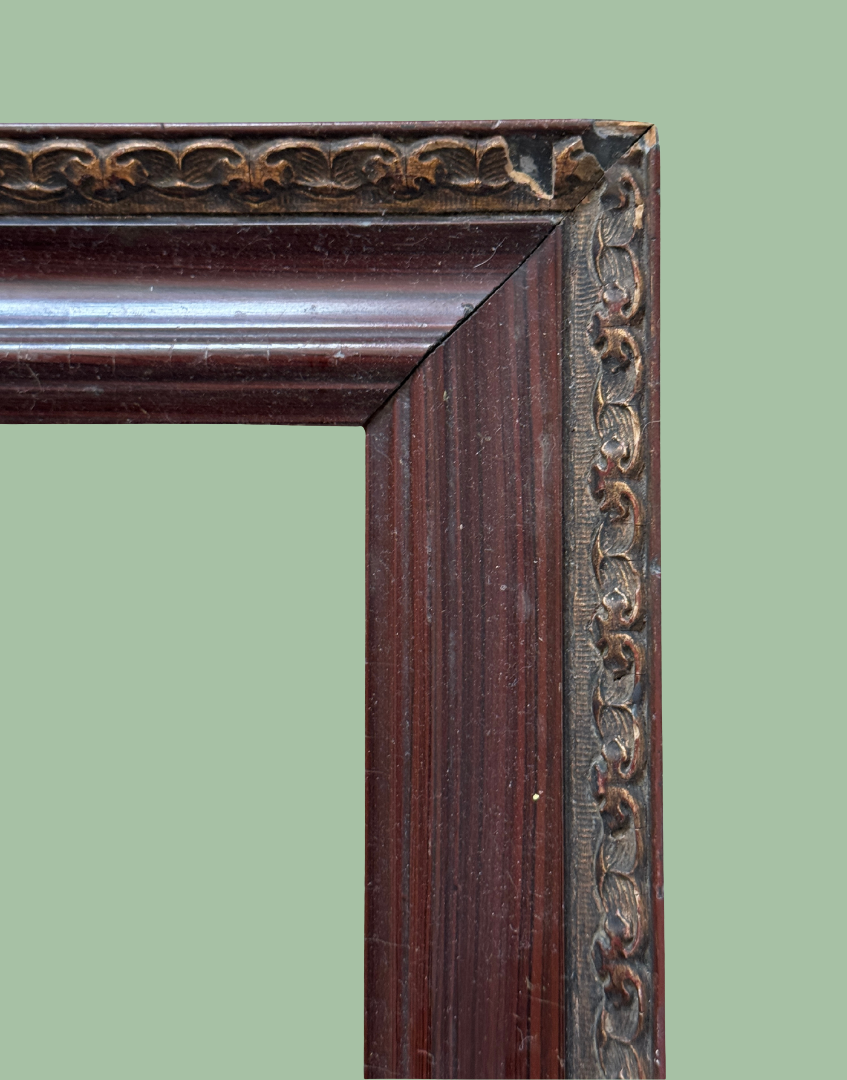 Close up of antique wood frame corner with decorative metal detailing and age wear.