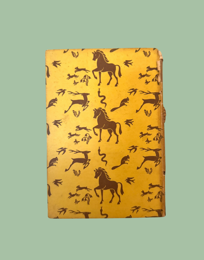 A vintage hardcover notebook or journal with a golden-yellow cover decorated with dark brown silhouettes of horses, deer, and snakes, shown against a solid sage green background.